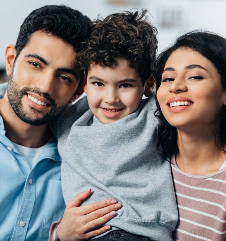 happy-latin-family-hugging-while-looking-at-camera